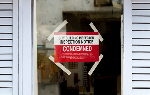 Front door of a house with a condemned sign posted on it.