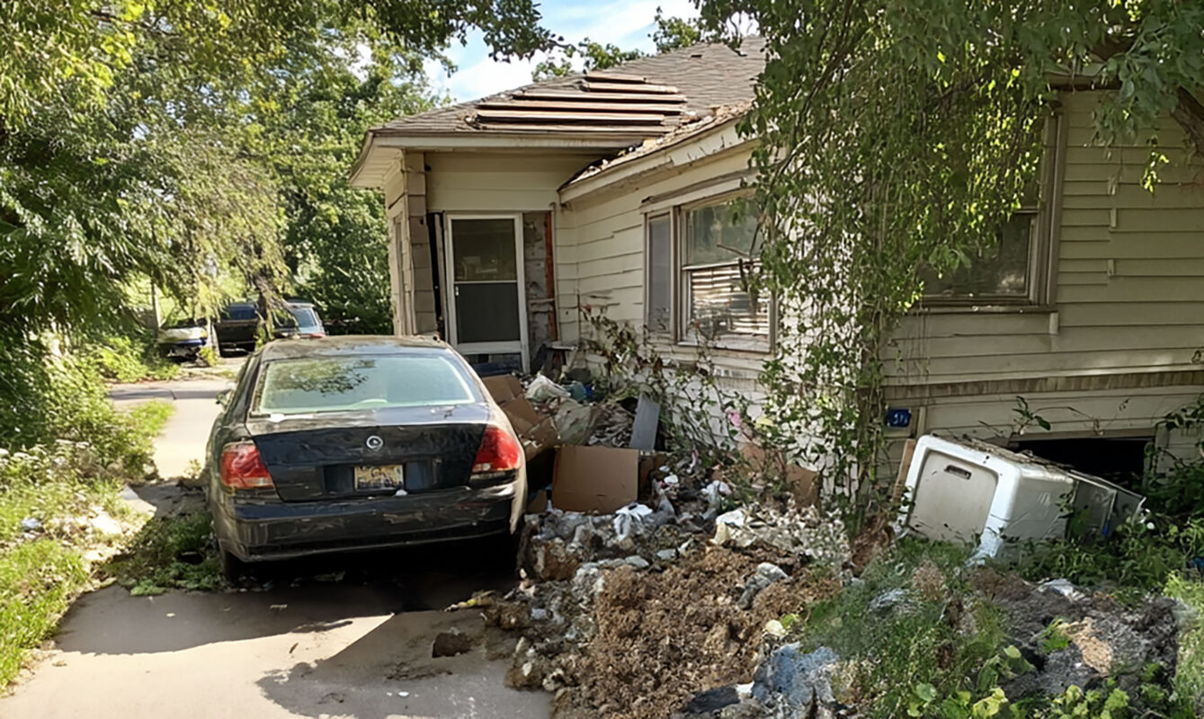 Exterior of a cluttered home with signs of neglect, linked to a hoarding case.
